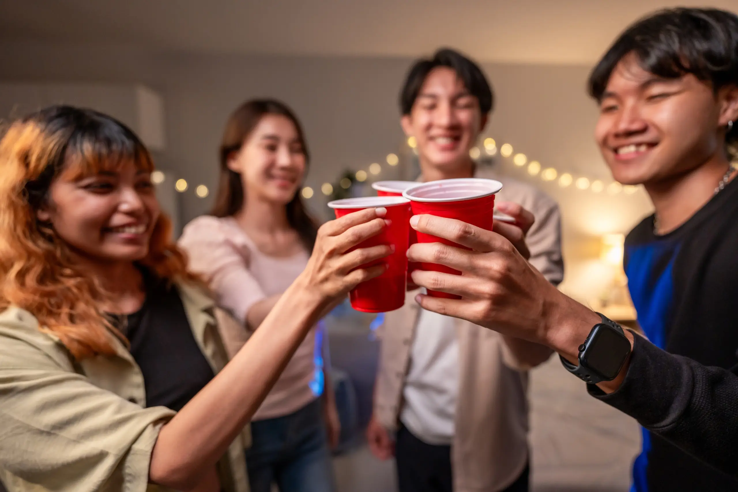 Two friends at a holiday gathering holding sparkling water and laughing, emphasizing sober socializing Staying sober at holiday parties with supportive friends